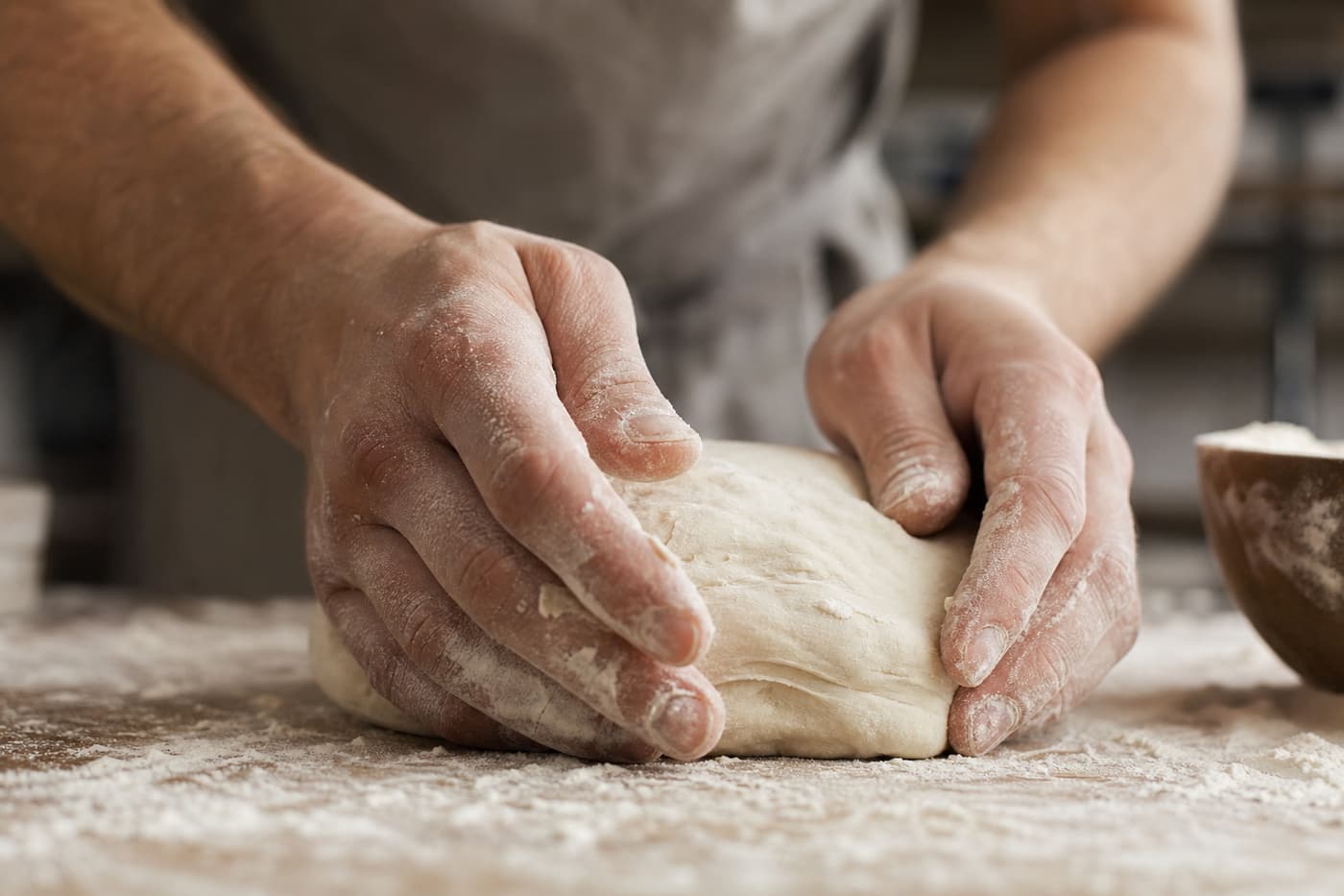 Flour-dusted hands shaping dough